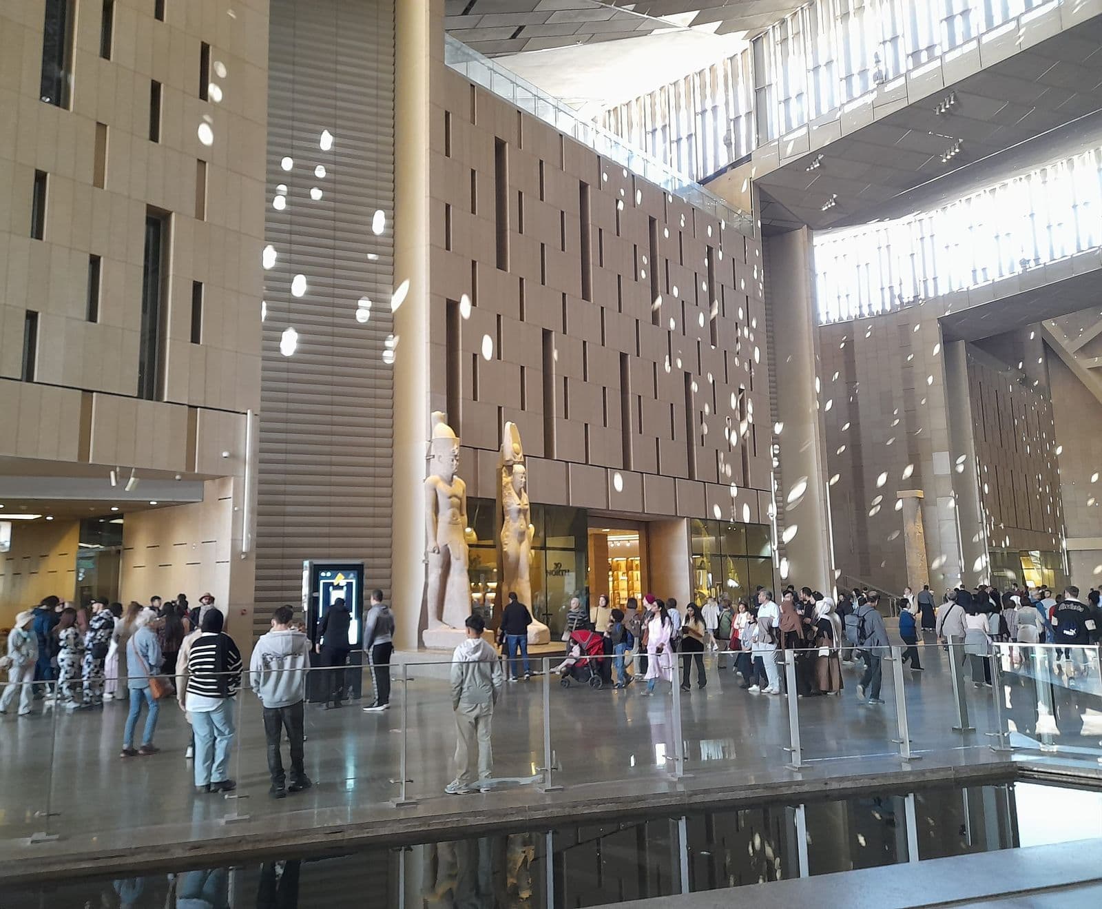 Visitors in the tall atrium of the Grand Egyptian Museum