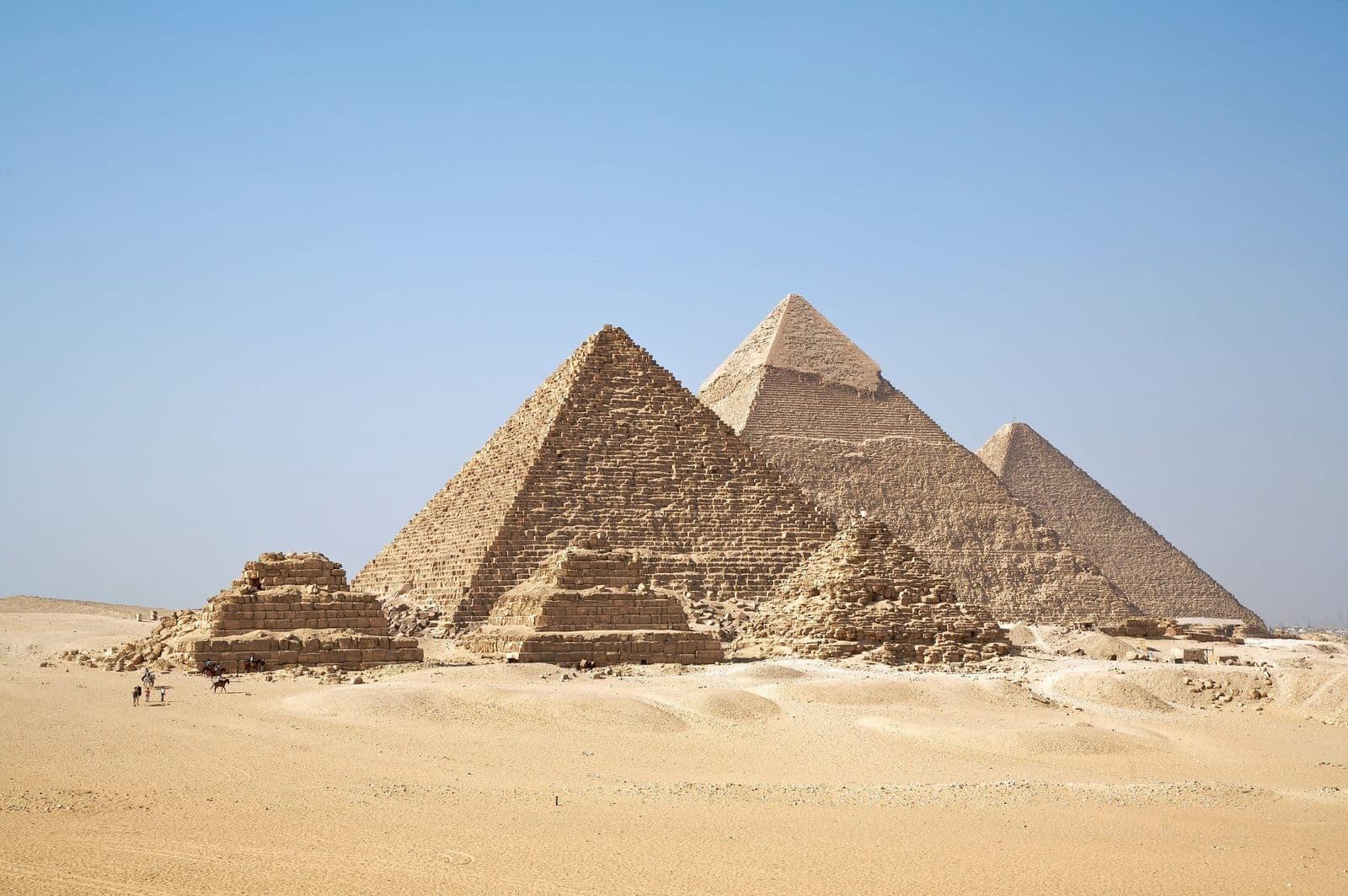 The three Pyramids of Giza and the small queens' pyramids under a clear blue sky