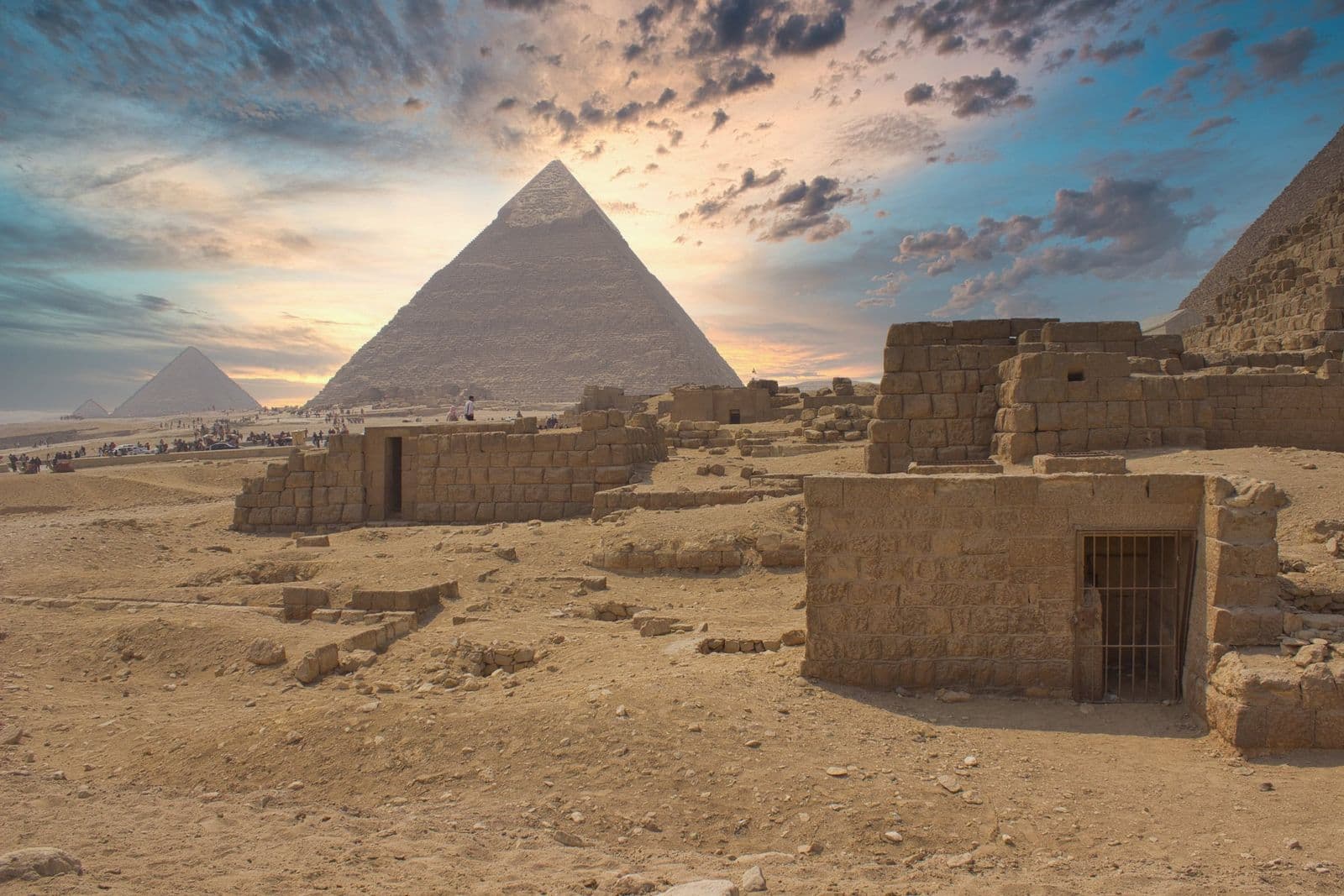 Pyramids of Giza and ancient stone tombs beneath a colourful sunset sky