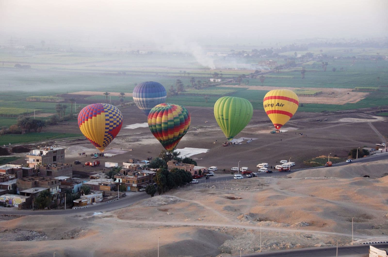 Colourful hot-air balloons over the green fields of Luxor's West Bank