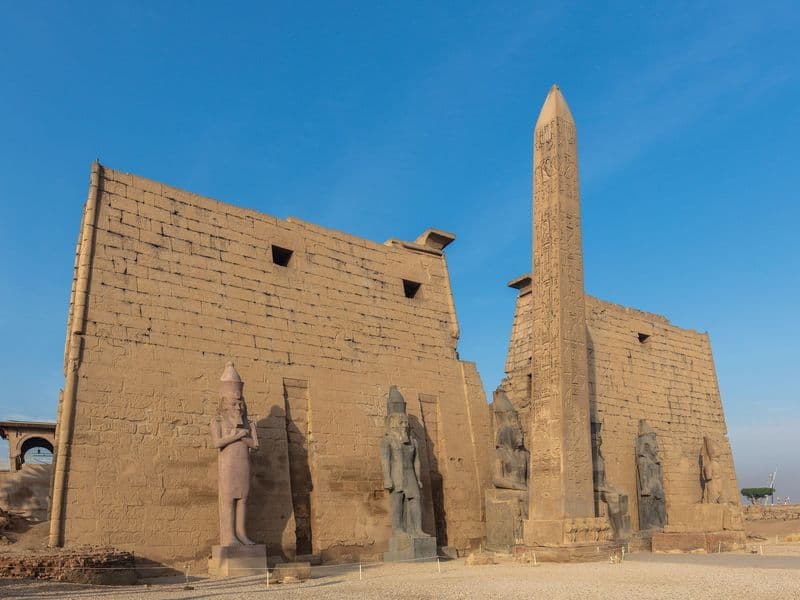The great pylon and obelisk of Luxor Temple against a blue sky