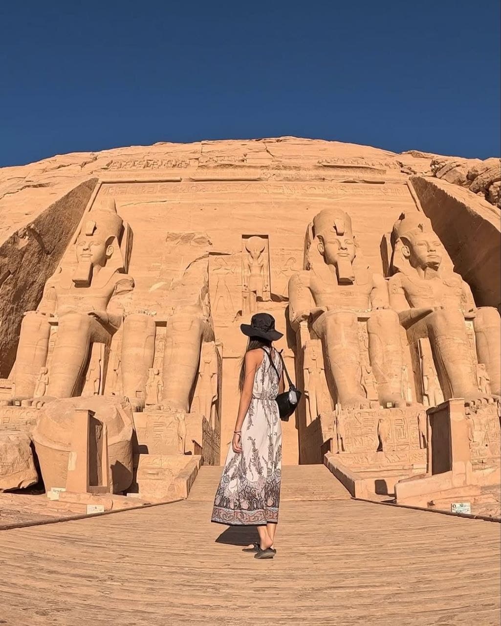 A traveler facing the four seated colossi of Ramesses II at Abu Simbel