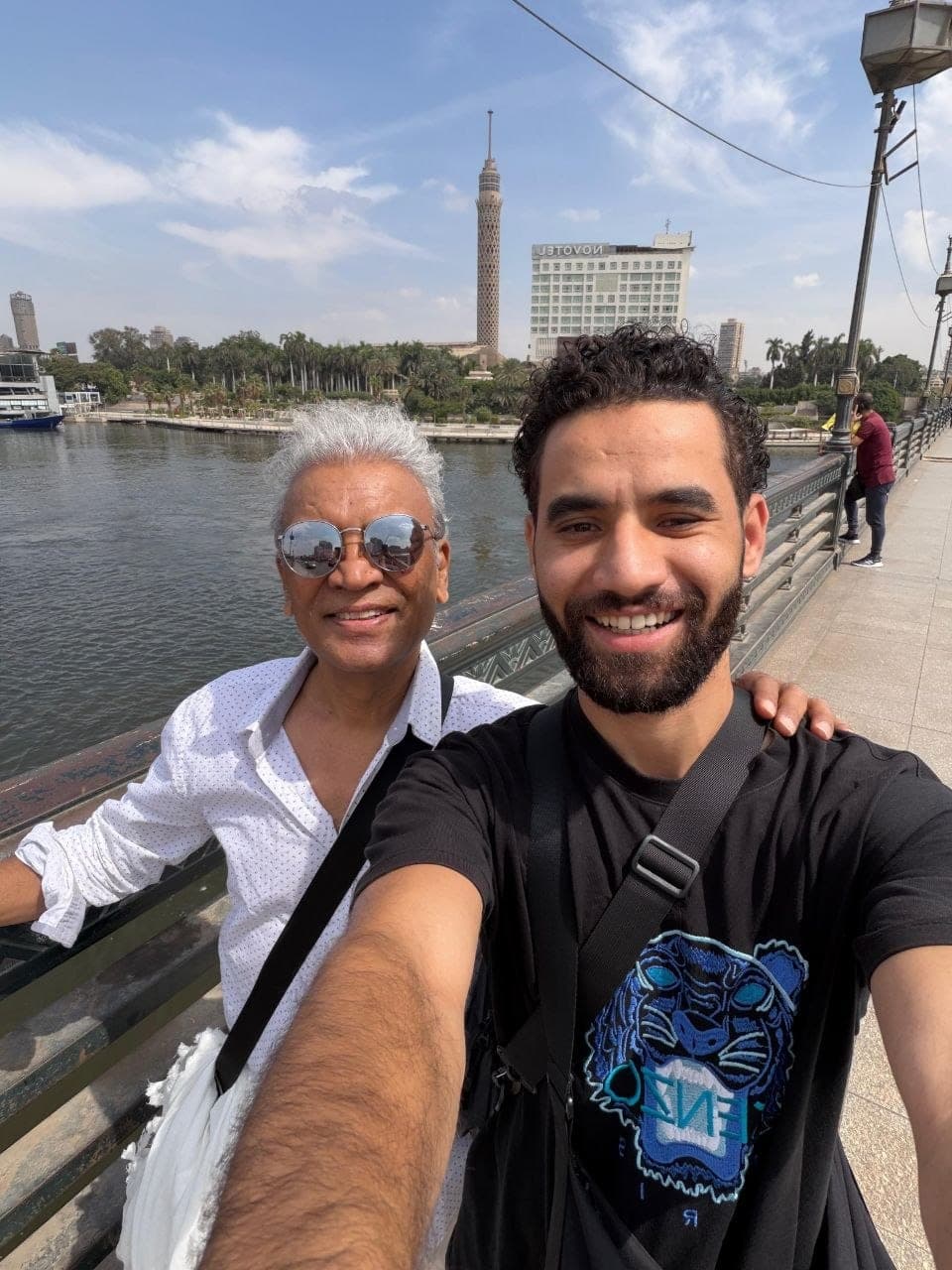 Amr with a traveler on the Nile corniche in Cairo, Cairo Tower behind