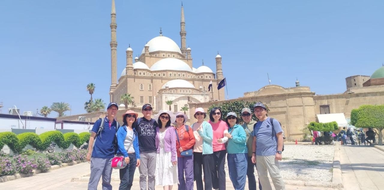 A group of travelers with Amr at the Cairo Citadel, the Muhammad Ali Mosque behind