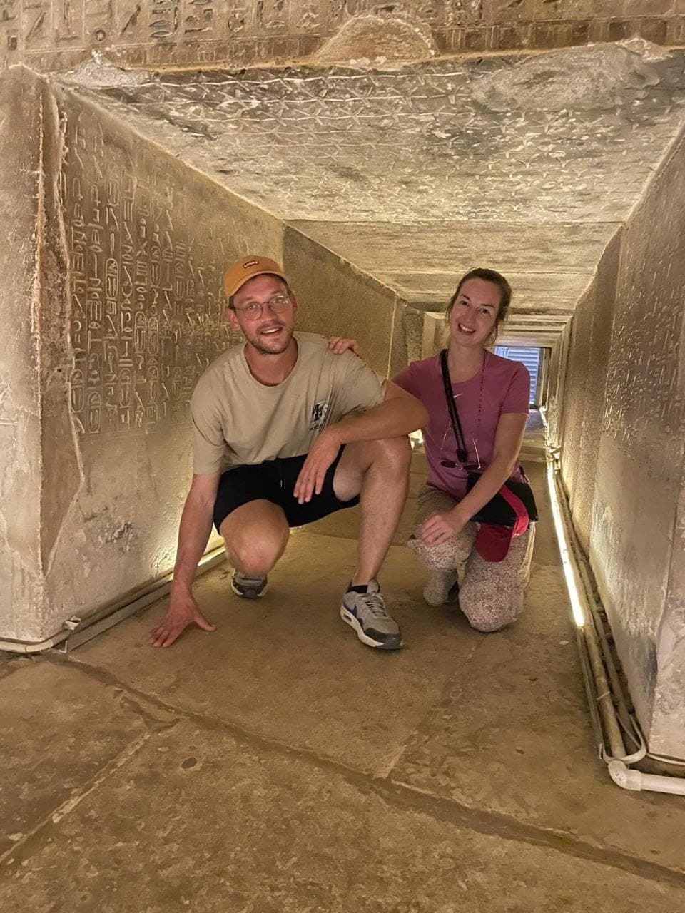Two travelers beside a huge granite box in the Serapeum tunnels at Saqqara