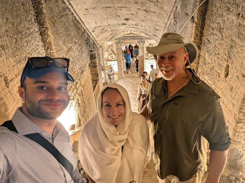 Tarek with two travelers inside a decorated tomb corridor at Saqqara