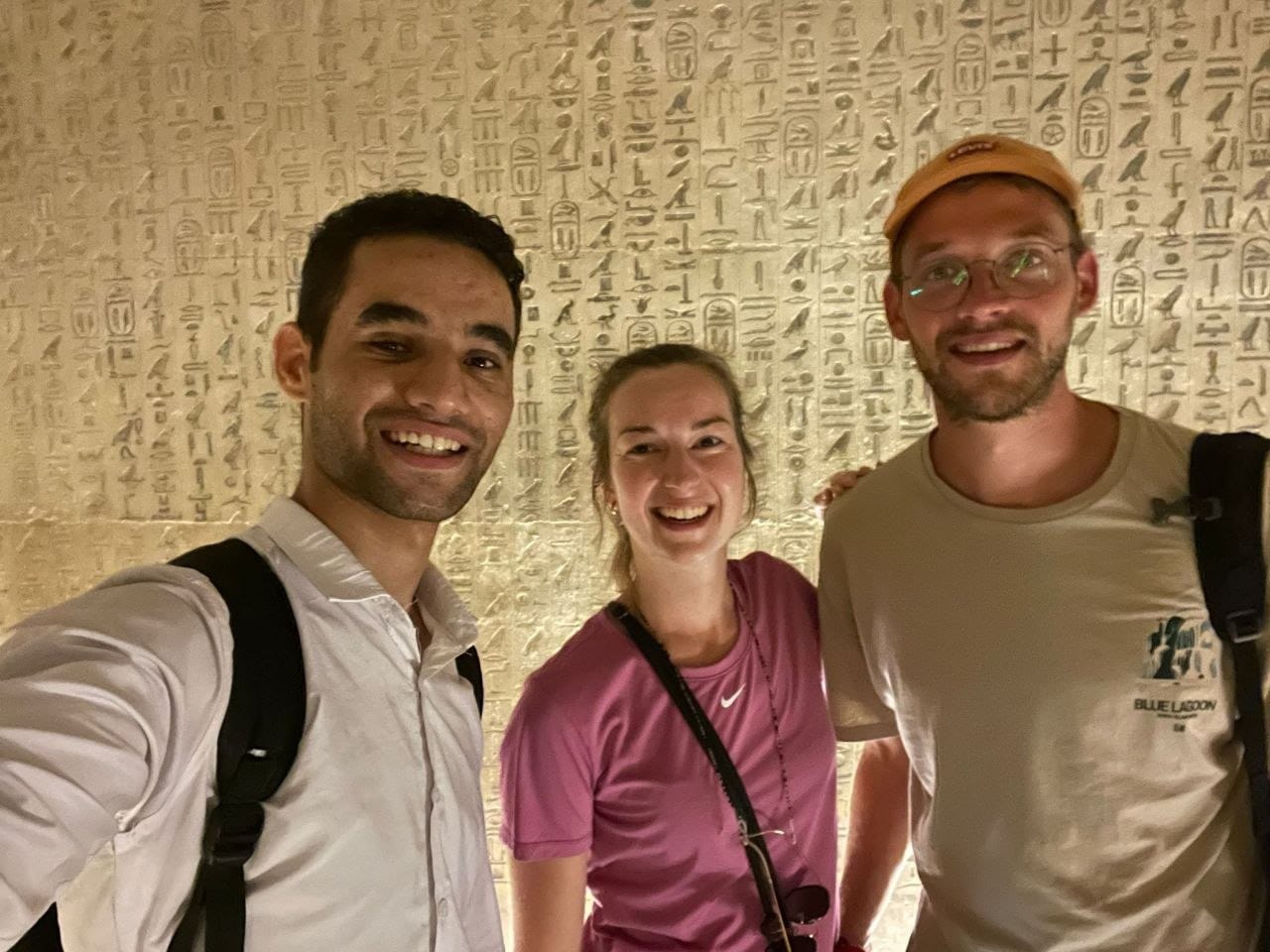 Amr with two travelers in front of a wall of hieroglyphs at Saqqara