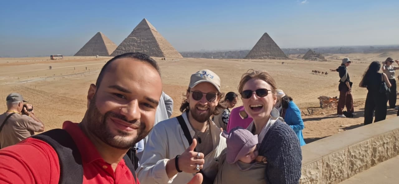 Tarek with a family on the Giza plateau, the three pyramids behind them