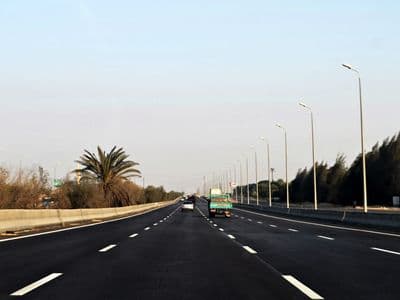 A wide, quiet section of the Cairo to Alexandria desert road lined with palms
