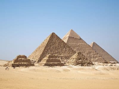 The three Pyramids of Giza and the small queens' pyramids under a clear blue sky