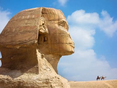 Side view of the Great Sphinx's head against a blue sky with white clouds