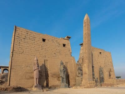 The great pylon and obelisk of Luxor Temple against a blue sky