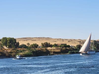 A dahabiya sailing below golden desert hills on the Nile