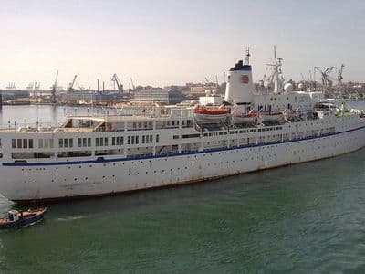 A white passenger ship sailing into the harbour of Port Said